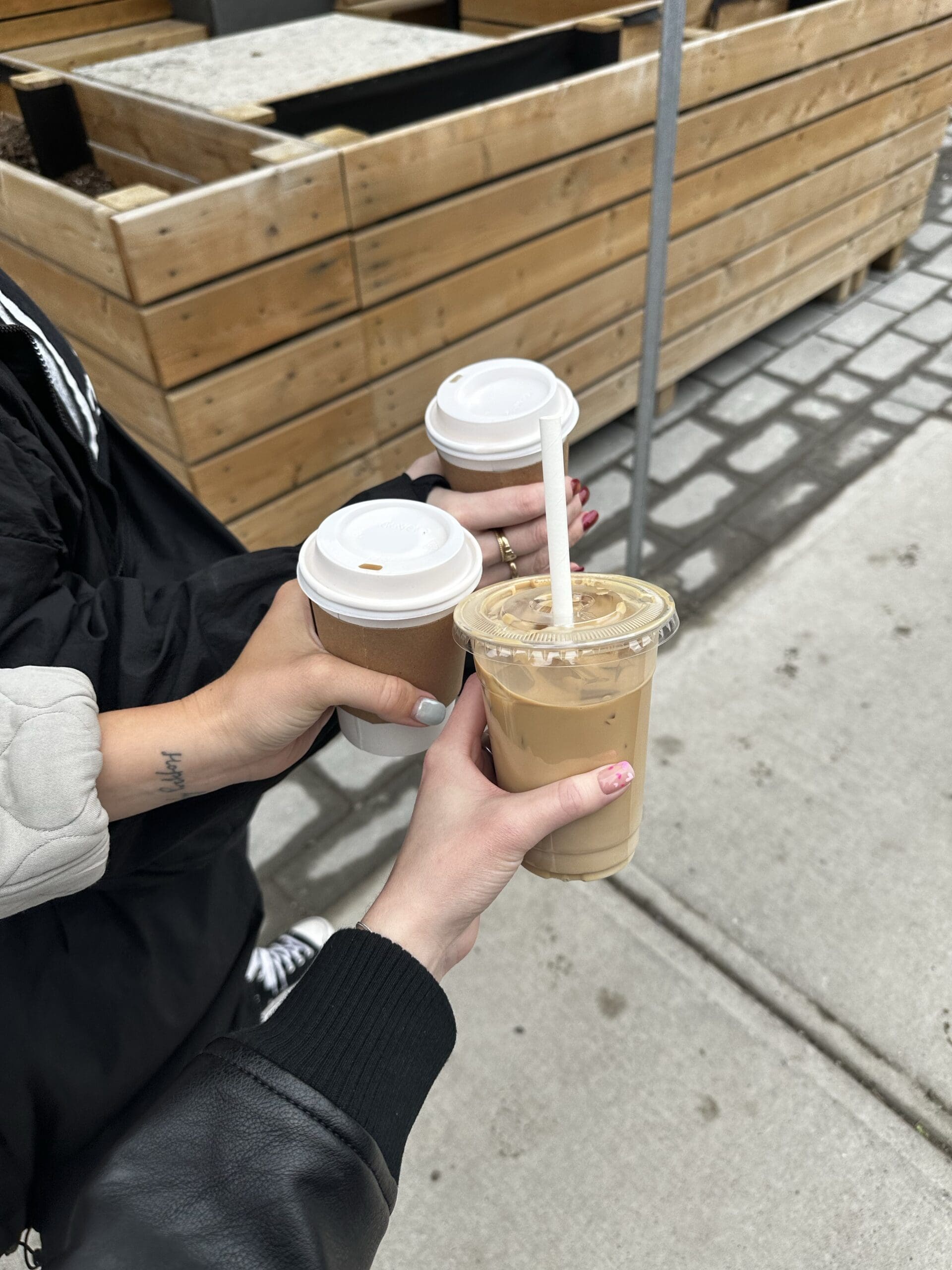 Three hands holding takeaway coffee cups, symbolizing teamwork, delegation, and outsourcing tasks for increased productivity.